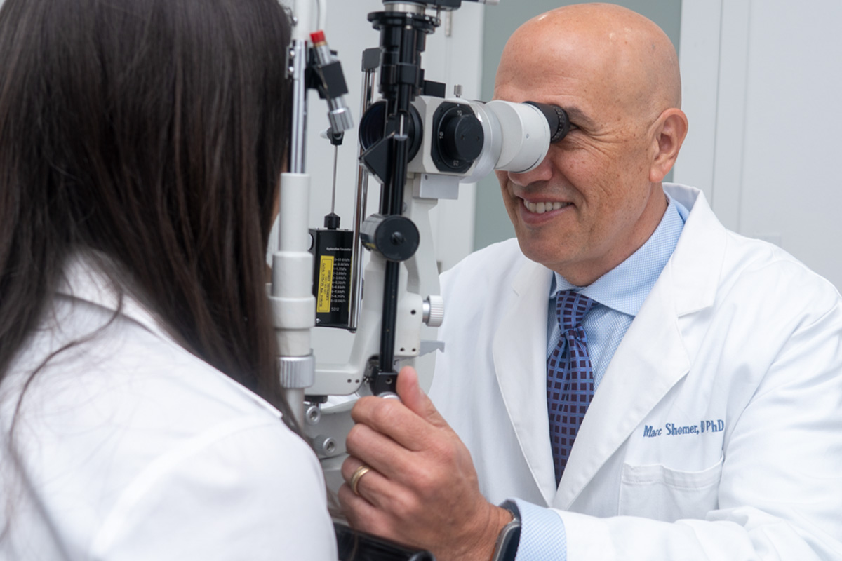 Eye doctor performing a slit lamp eye exam on a patient during a clinical visit.
