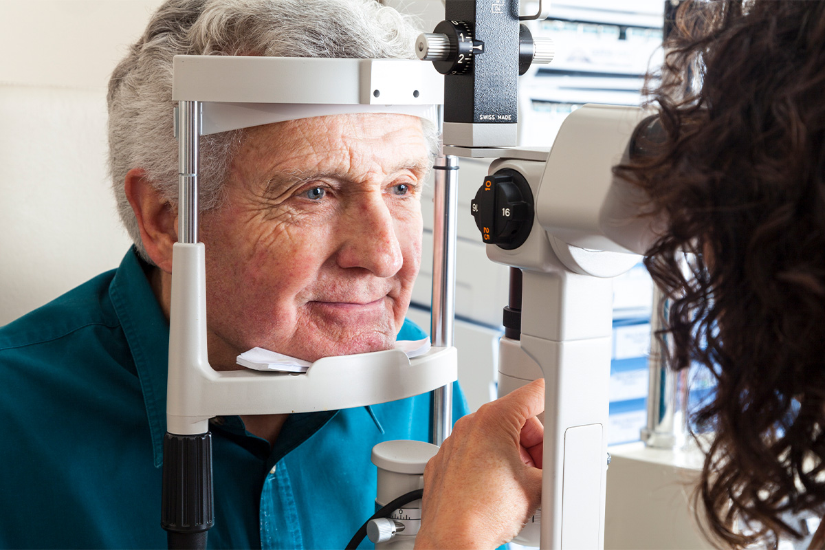 Older man receiving a slit lamp eye exam during an ophthalmology appointment.