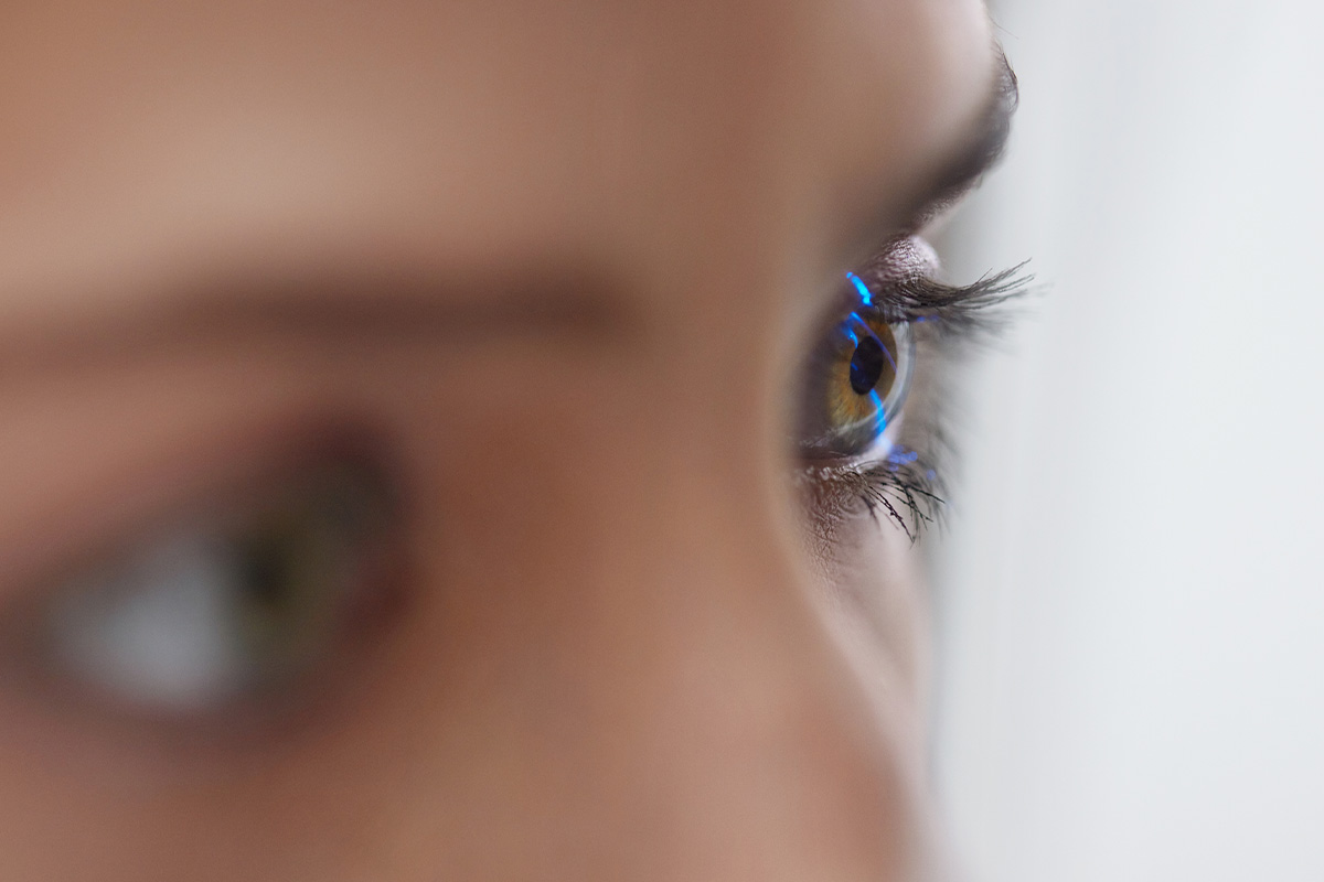 Primer plano extremo del ojo de un paciente con luz de diagnóstico reflejada durante un examen de la vista.