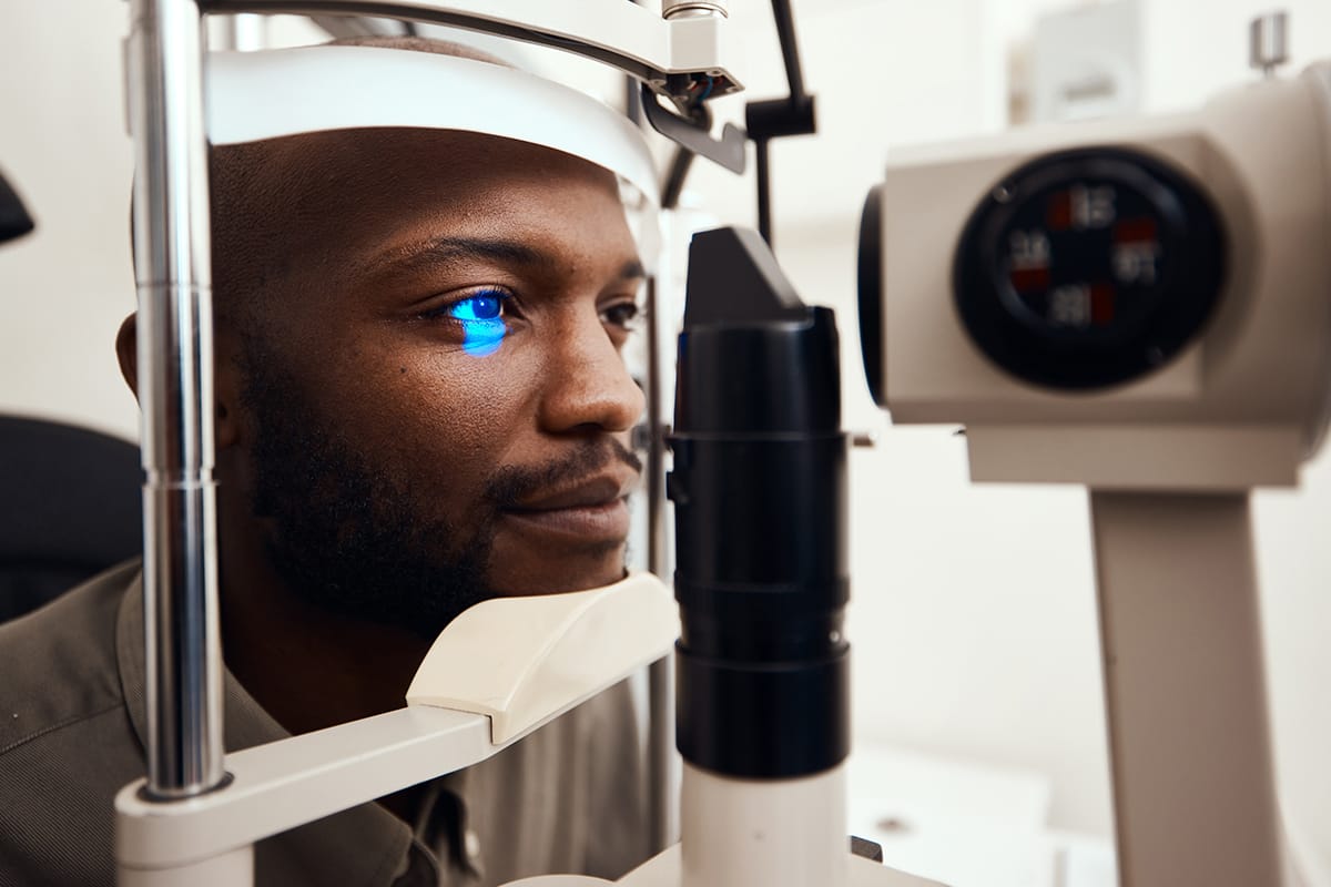Hombre durante un examen de ojos con lámpara de hendidura y luz azul de diagnóstico en una clínica oftalmológica.